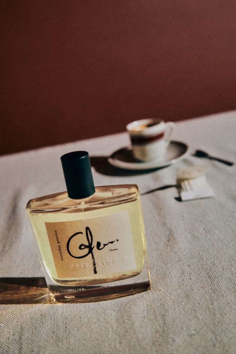 Everyday Poetics fragrance bottle with a cup of coffee in the background.